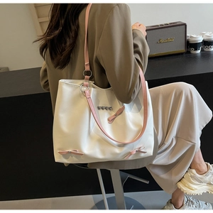 Detail of white PU tote bag with silver heart buckles and pink ribbon bow accents