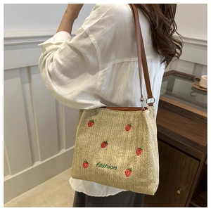 Détail de la broderie fraise et bandoulière en cuir sur sac cabas de plage tressé