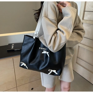 Close-up of black tote bag with white bows and silver heart studs for a stylish contrast