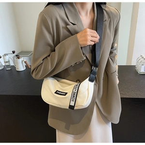 Detail of a beige half-moon crossbody bag with litchi grain leather and nylon strap