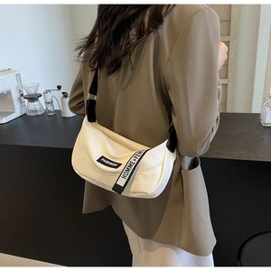 Detailed shot of white litchi textured hobo bag with fashion lettered strap decoration