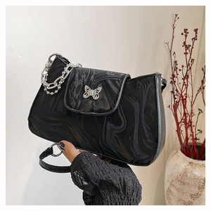Close-up of black marble crescent bag featuring a silver butterfly buckle and chain
