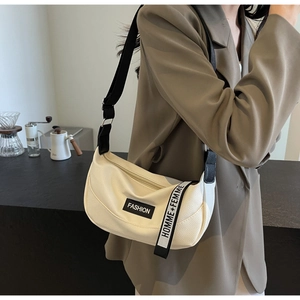 Detail view of cream-white crescent crossbody bag with fashion strap and textured finish