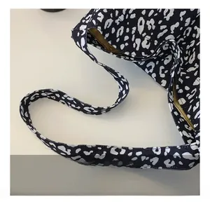 Close-up of the wide fabric shoulder strap on a black and white leopard print tote bag