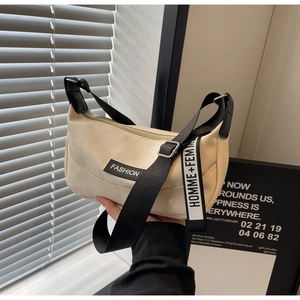 Close-up of beige lychee leather saddle bag with black straps and logo detail