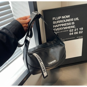 Detail of black lychee grain leather crossbody bag with lettered wide nylon strap