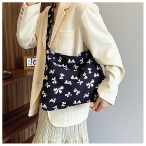 Detail of black canvas tote bag with white bow pattern and wide comfortable shoulder strap