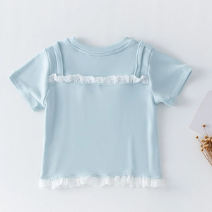 Détail du tissu côtelé bleu clair et broderie anglaise blanche sur le t-shirt fille