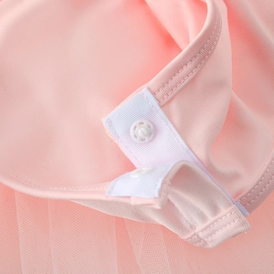 Detailed close-up of pink tulle ballet dress featuring white plastic snap buttons at the crotch