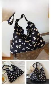 Detail of large canvas tote bag featuring white bow patterns on black durable fabric