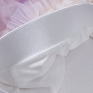 Close-up of pink purple gradient tulle layers and white satin waistband on a tutu skirt