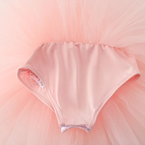 Detailed close-up of pink ballet dress showing multilayer tulle mesh and interior care label