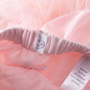 Détail de la taille élastique avec bouton réglable et étiquette sur la jupe en tulle