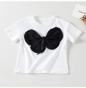 Dettaglio della maglietta bianca da bambina con grande fiocco nero e centro in strass