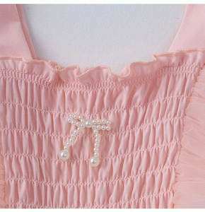 Détail de robe rose avec corsage froncé élastique et nœud en perles élégant