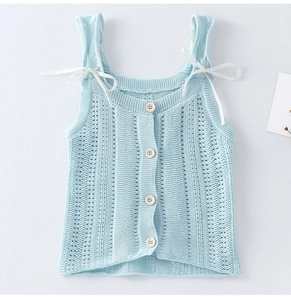 Dettaglio del gilet in maglia azzurro con motivi traforati e piccoli bottoni in legno