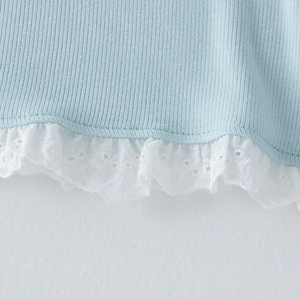 Détail de maille côtelée bleu clair avec broderie en dentelle fleurie blanche sur l'ourlet