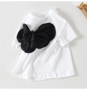 Primo piano di una T-shirt bianca da bambina con un grande fiocco in tulle nero 3D