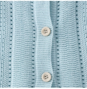 Dettaglio di maglia traforata azzurra con due bottoni opachi color crema