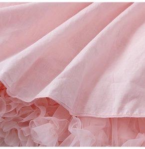 Détail du tissu en coton rose et de l'ourlet en tulle multicouche de la robe de fête