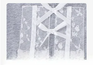 Close-up of girls' grey knit top featuring white lace trim and three satin bow details