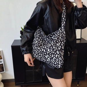 Large leopard print tote bag with black strap worn by model in chic urban outfit