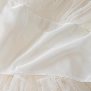 Détail du tissu en soie crème et du tulle multicouche aux bords ondulés délicats