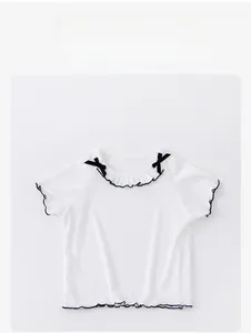 Close-up of white ribbed short sleeve top with lace trim and black bow details