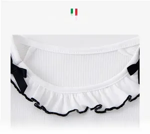 Close-up of white ribbed neckline with lace trim and elegant black ribbon bows