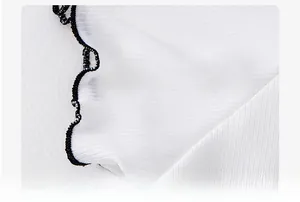 Detail of white ice silk shirt sleeve featuring delicate black ruffled lettuce edge trim