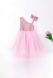 Flat lay of pink sequin girls dress with mesh skirt and matching bow headband