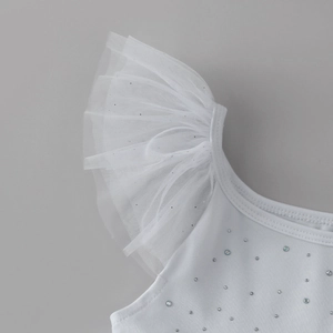 Détail d'une robe blanche pour fille avec manches à volants et strass argentés brillants