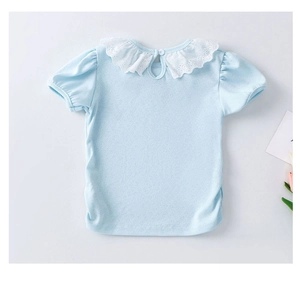 Détail d'un haut bleu clair pour fille avec col en dentelle blanche et bouton au dos