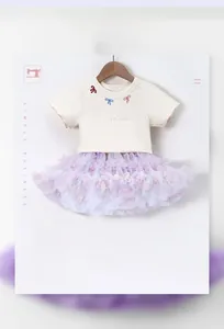 Detail of girls' ivory t-shirt with bow embroidery and purple layered mesh tutu skirt