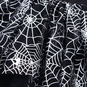 Close-up of black tulle fabric featuring shimmering silver spider web patterns