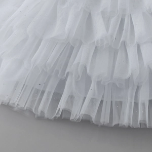 Détail d'une robe gâteau en tulle blanc multicouche avec paillettes argentées et volants