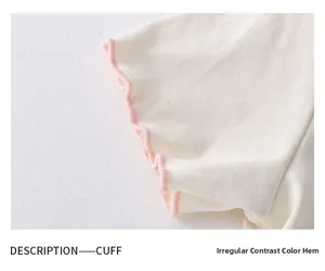 Detail of knit cuff with pink irregular contrast stitching and wavy ruffle edges