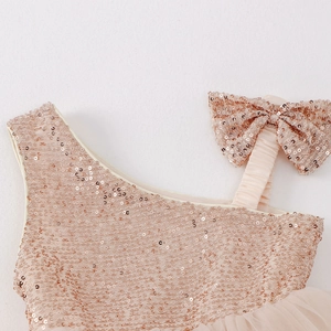 Detail of sequined bow shoulder strap on a sparkling champagne flower girl dress