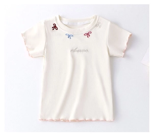 Detail of embroidered colorful bows and lettuce edge trim on children's cream t-shirt