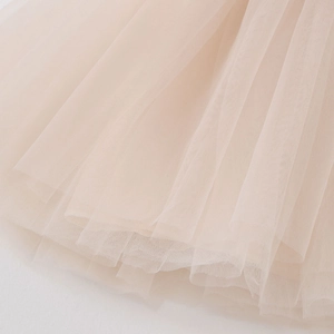 Close-up of layered champagne pink tulle fabric showing delicate mesh and soft ruffles