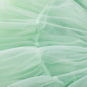 Close-up of light green layered mesh tulle fabric with fine pleated stitching details