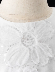 Dettaglio dell'abito da cerimonia bianco per bambina con fiori 3D e paillettes argento