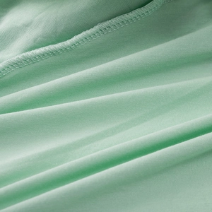 Close-up of mint green soft knitted fabric showing professional overlock stitch detail