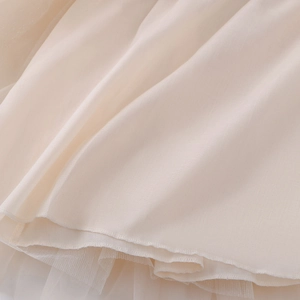 Detail of layered tulle fabric and smooth silk lining on beige flower girl dress