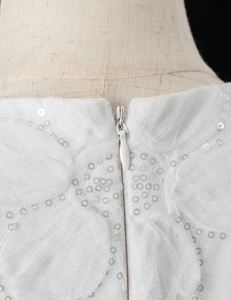 Dettaglio dell'abito in rete bianca con paillettes d'argento e cerniera invisibile