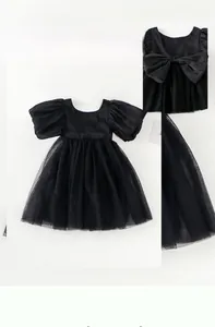 Detail eines schwarzen Mädchen-Tüllkleides mit Puffärmeln und großer Schleifenverzierung