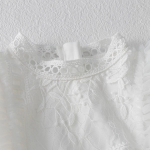 Dettaglio ravvicinato dello scollo dell'abito in pizzo bianco con ricami floreali e tulle