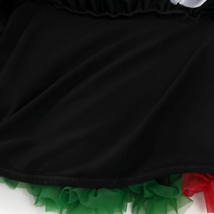 Detailaufnahme des Mädchenkleides aus schwarzem Strick mit rot-grünen Tüll-Rüschenbesatz