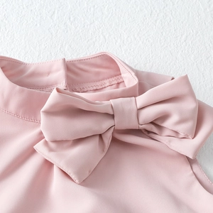 Detail of pink tiered dress showing the elegant stand-up collar and delicate bow design