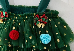 Detail of green mesh Christmas dress featuring gold stars and festive bell ornaments